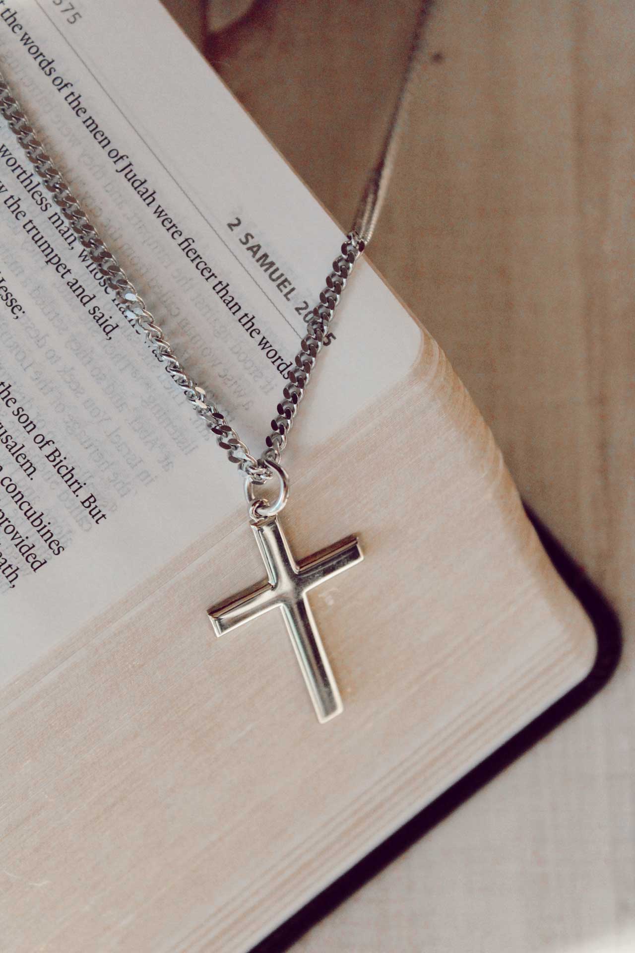 a cross necklace sitting on top of an open book.