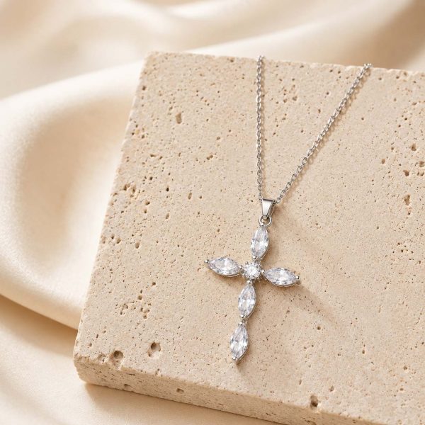 silver cross necklace on stone display