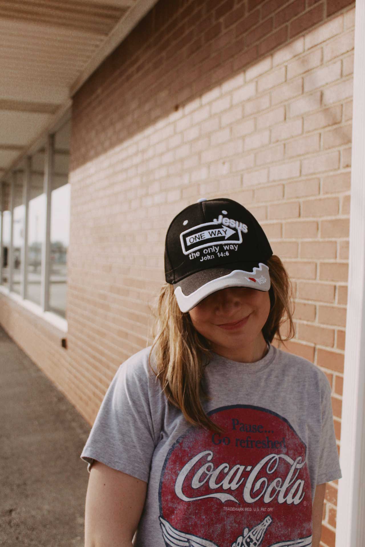 One way Jesus hat on girl in front of brick wall Swanson christian