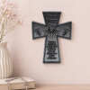 grey wall cross on a beige wall with plant to left