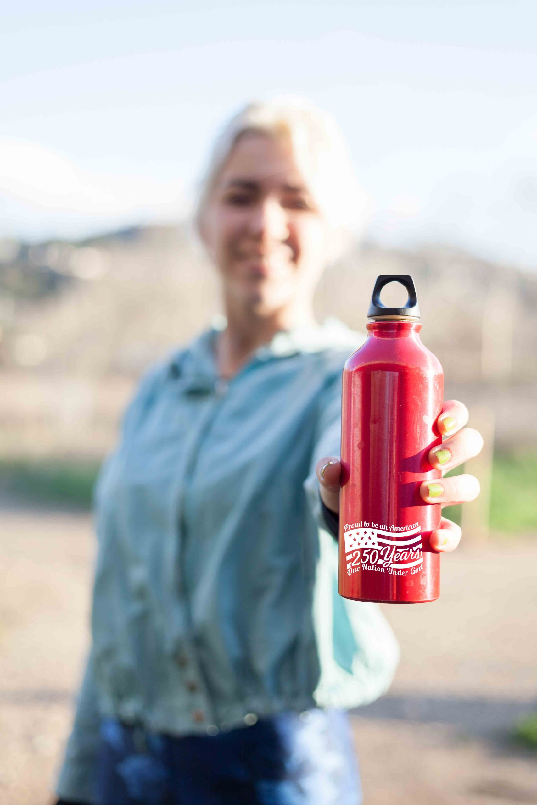 A Happy smiling sports woman passing a water bottle to camera