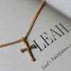Beautiful gold-tone cross necklace resting on a page featuring the word “LEAH” and the phrase “God’s Faithfulness,” creating a soft and elegant devotional setting. The delicate cross design and warm gold finish symbolize faith, hope, and spiritual encouragement, making it a meaningful gift or everyday expression of Christian belief.