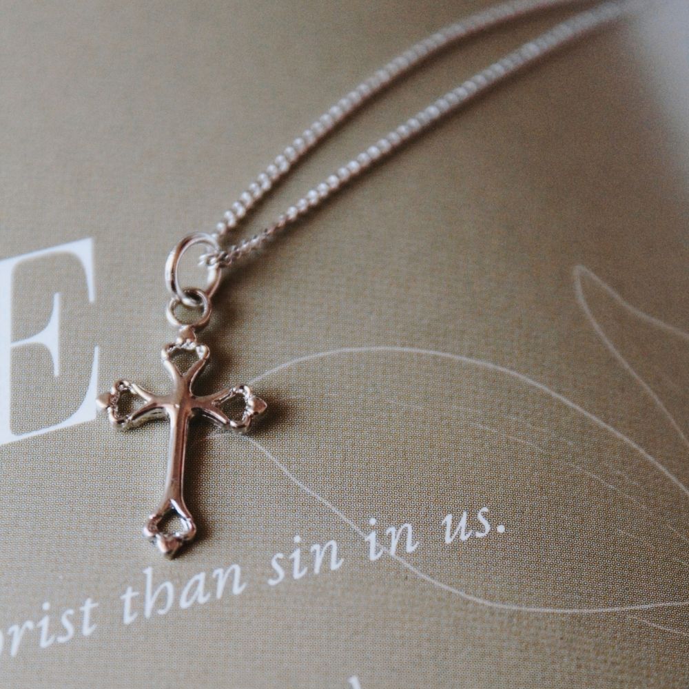 Beautiful gold-tone cross necklace resting on a page featuring the word “LEAH” and the phrase “God’s Faithfulness,” creating a soft and elegant devotional setting. The delicate cross design and warm gold finish symbolize faith, hope, and spiritual encouragement, making it a meaningful gift or everyday expression of Christian belief.