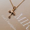 Delicate gold-tone cross necklace displayed on a Christian faith journal, highlighting the polished cross pendant and fine chain in a warm, elegant devotional setting.