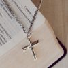 Classic silver-tone cross necklace resting on the pages of an open Bible, creating a peaceful and timeless faith-inspired scene. The polished cross pendant and chain are highlighted against Scripture, symbolizing devotion, hope, and a daily walk with Christ. A meaningful Christian gift suitable for baptisms, confirmations, graduations, or everyday wear.