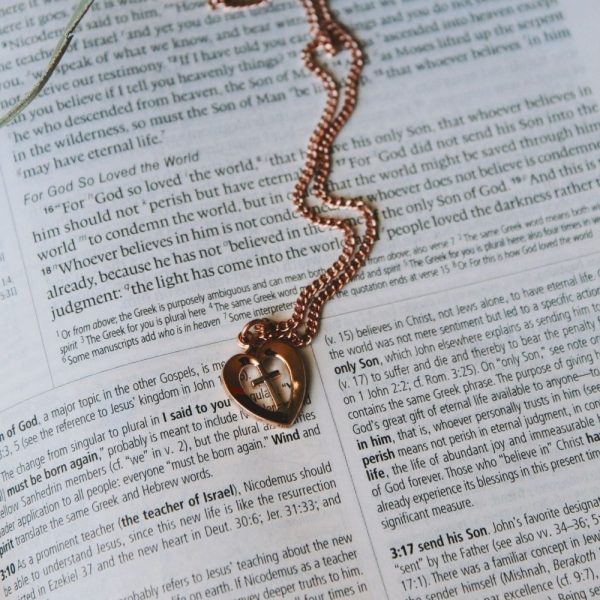 Rose gold-tone heart pendant necklace featuring a cross cutout resting on an open Bible. The warm metallic finish and visible Scripture create a meaningful faith-centered composition that symbolizes Christ’s love, redemption, and devotion. A beautiful Christian jewelry gift for women, perfect for encouragement, birthdays, confirmations, Mother's Day, or everyday wear.