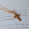 Gold-tone cross necklace resting on an open Bible page, Christian cross pendant jewelry, faith-inspired necklace with Scripture background, elegant religious jewelry for women, Christian gift necklace, devotional cross pendant, everyday faith accessory, inspirational Christian jewelry, gold cross necklace close-up.