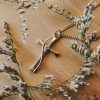 Twisted cross pendant necklace with crystal accent resting on a natural wood surface surrounded by delicate wildflowers, Christian faith jewelry, elegant cross necklace, inspirational religious pendant, gold-tone cross charm, spiritual gift for women, floral faith accessory, devotional jewelry photography, meaningful Christian keepsake.