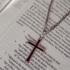 Silver cross pendant necklace resting on an open Bible, Christian faith jewelry, elegant silver cross necklace, religious pendant with chain, inspirational Christian gift, devotional jewelry for men and women, Bible verse background, spiritual keepsake necklace, faith-based accessory, meaningful cross charm close-up.