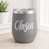 Gray insulated tumbler featuring a white “Chosen” Christian vinyl decal, displayed on a light wood desk in a bright, minimalist home setting.