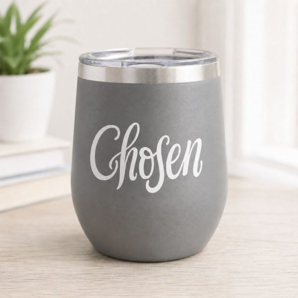 Gray insulated tumbler featuring a white “Chosen” Christian vinyl decal, displayed on a light wood desk in a bright, minimalist home setting.