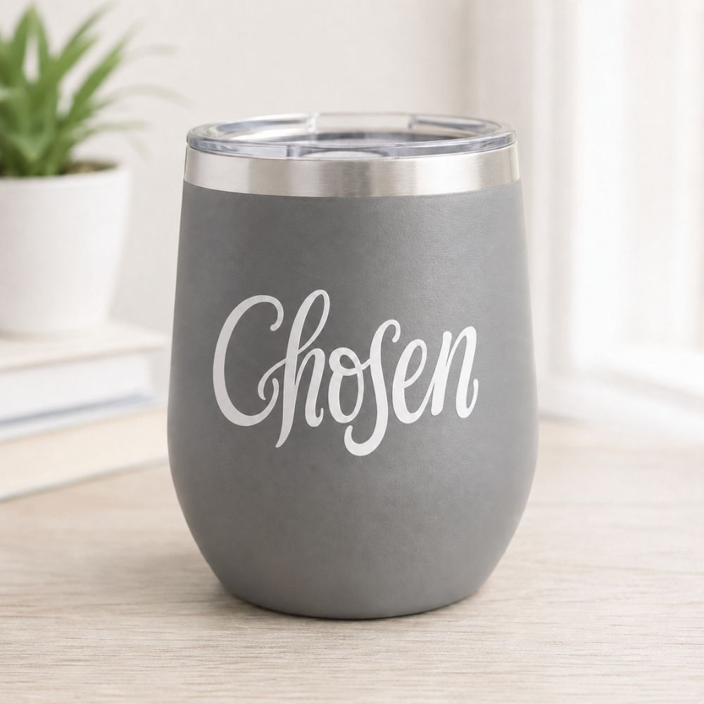 Gray insulated tumbler featuring a white “Chosen” Christian vinyl decal, displayed on a light wood desk in a bright, minimalist home setting.
